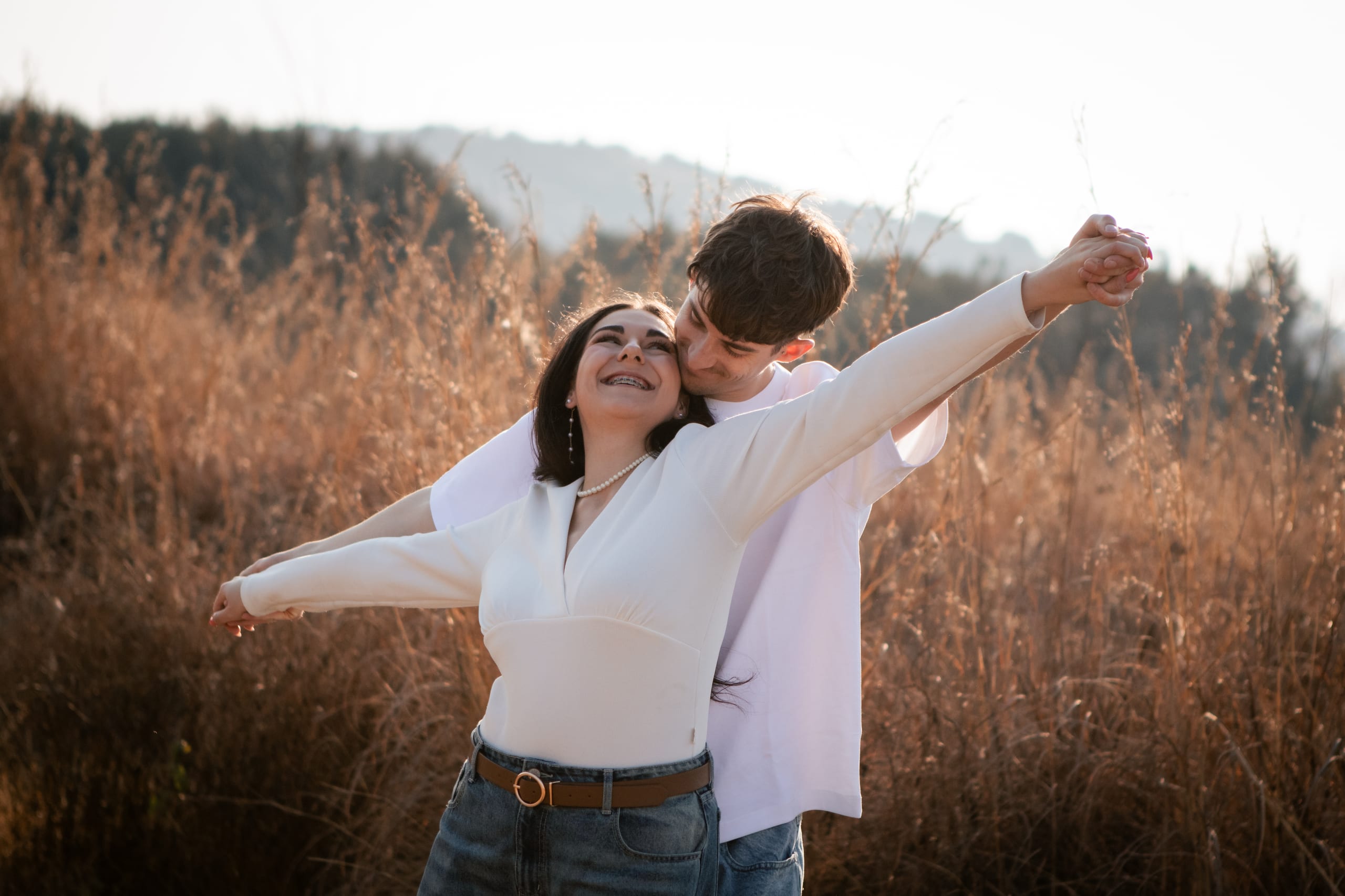 Shannon laughing with her arms open while Gareth leans in behind her in a field