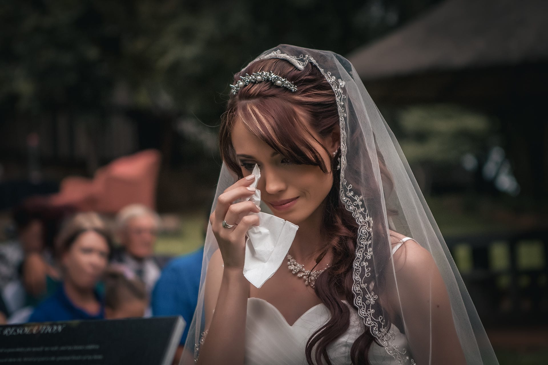 A bride wiping away a tear during her wedding day
