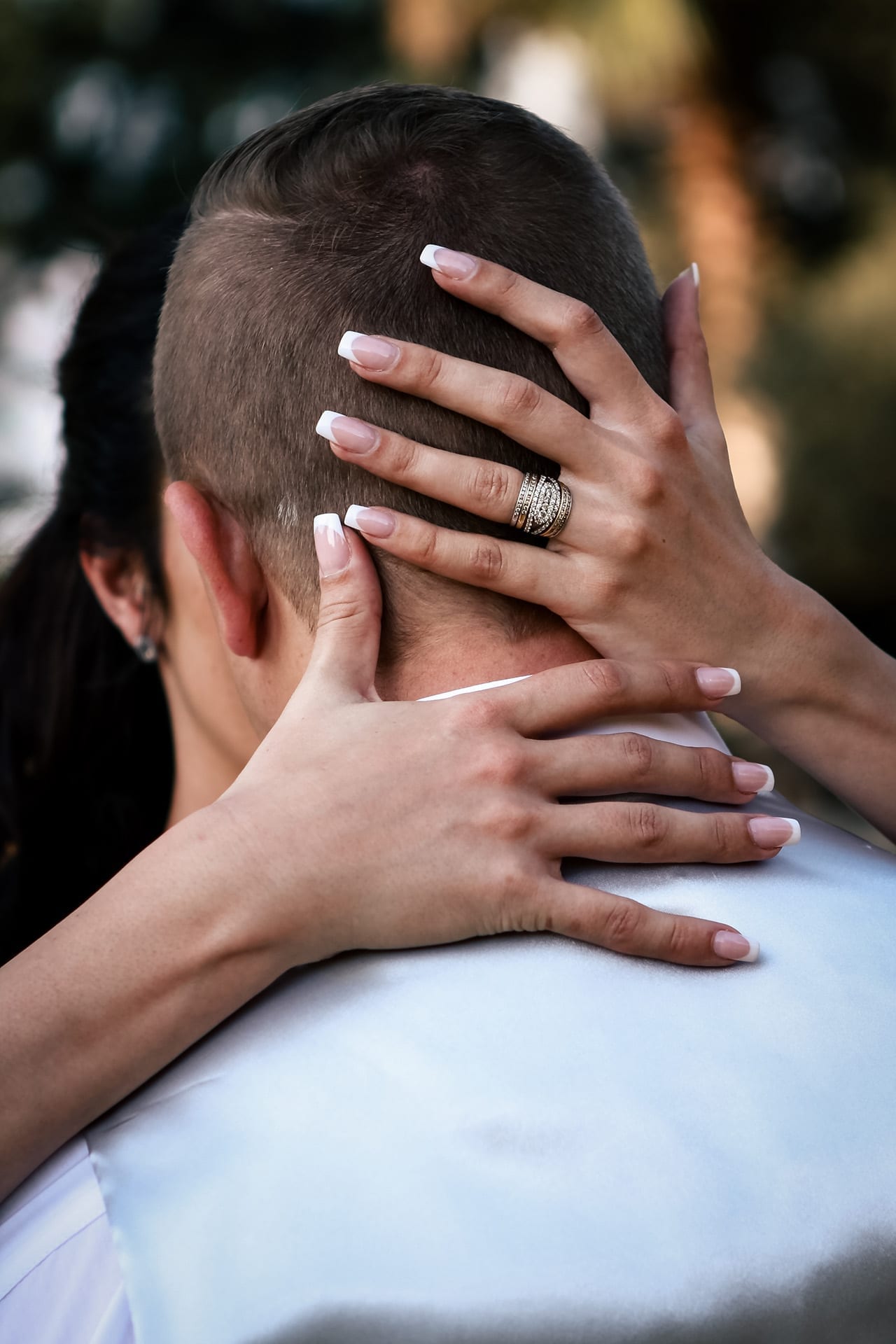 A bride's hands resting around her partner with her wedding rings visible