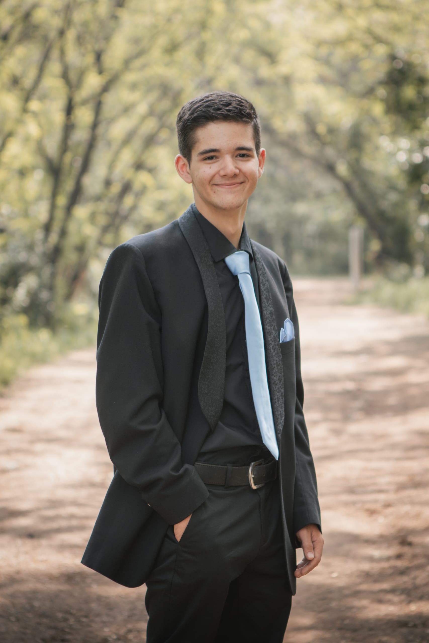 Matric farewell partner posing alone in a black suit with a blue tie