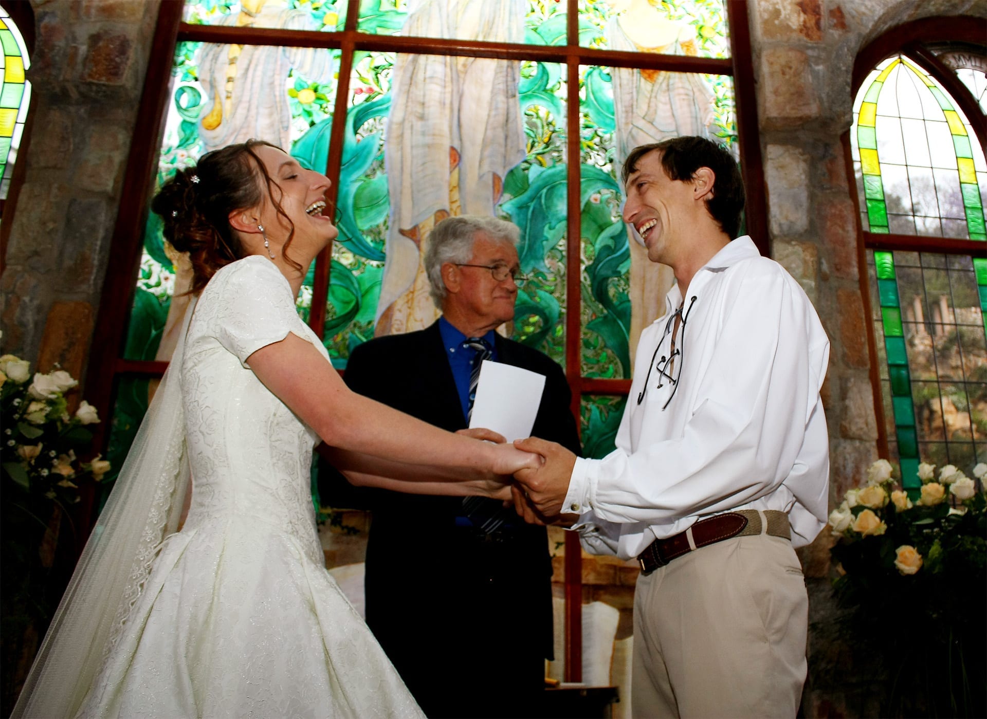 A newly married couple laughing together during their wedding ceremony