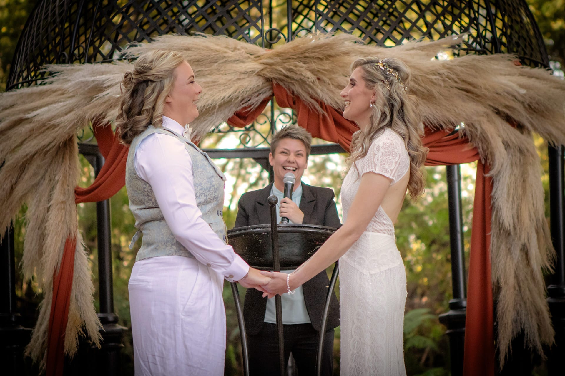 A couple holding hands and smiling during their wedding ceremony
